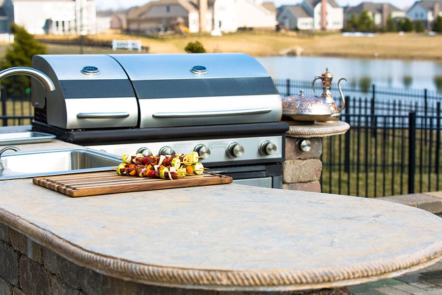 A closeup of a Springfield, Illinois modern outdoor kitchen with an ovular counter, sink and grill.