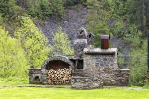An old stone stove with a smokehouse and firewood.